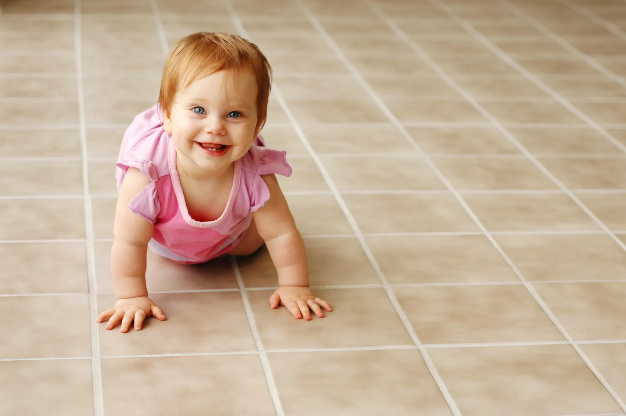 Baby safely playing on clean tile floor